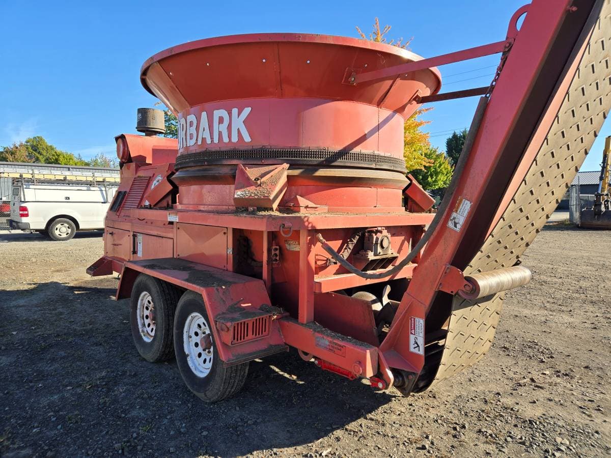 Red Morbark tub grinder on a trailer in an equipment yard. No person in the frame.